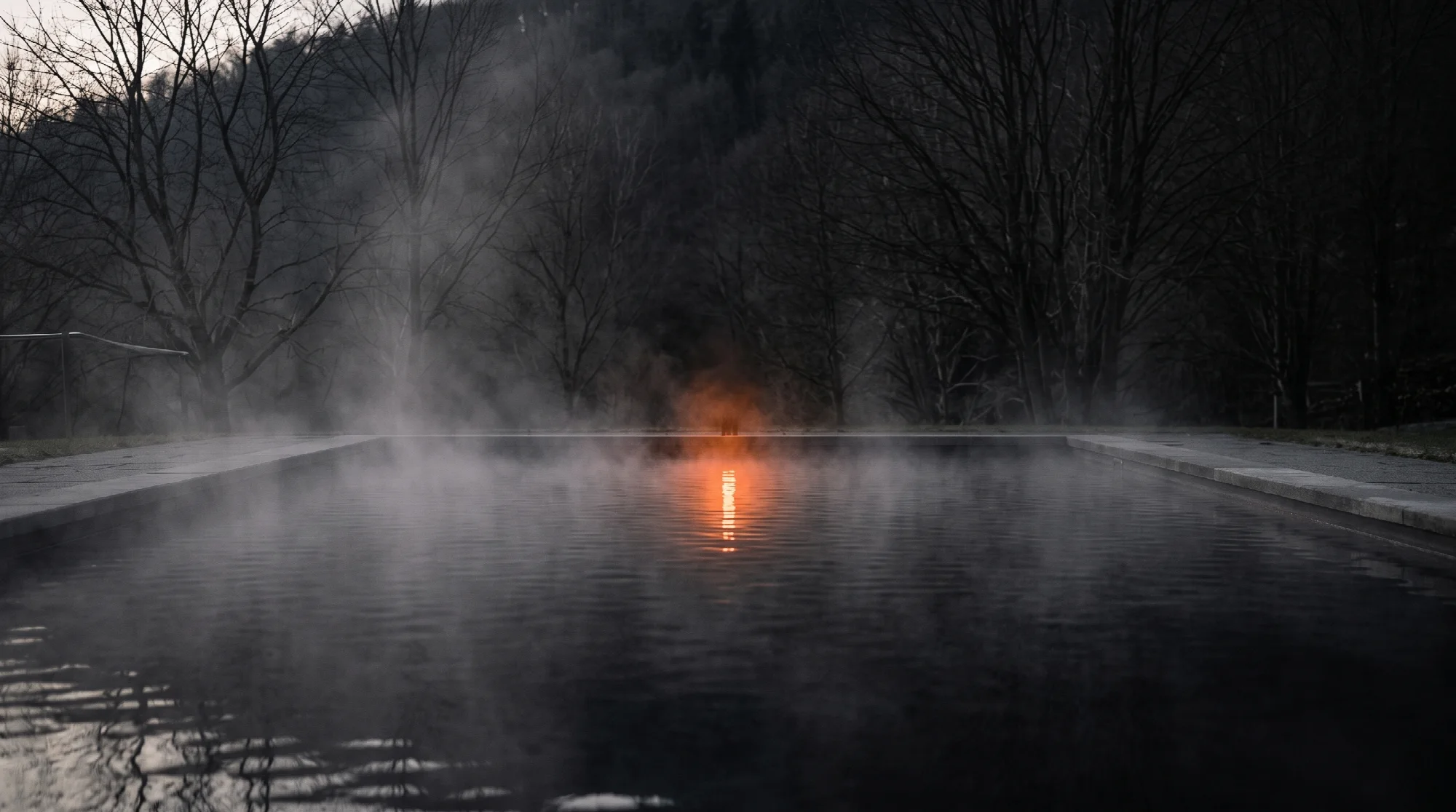 Steam rising from a heated outdoor pool at dusk